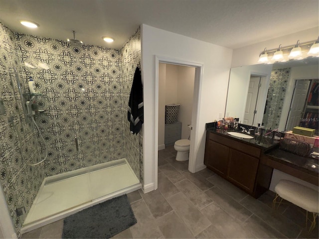 bathroom with vanity, toilet, and tiled shower