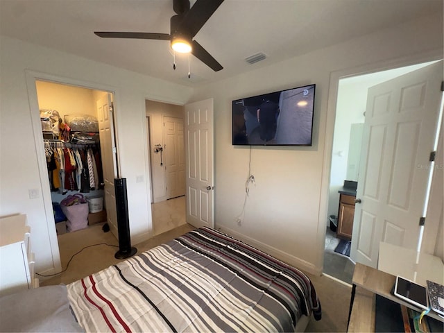 bedroom featuring a walk in closet, a closet, and ceiling fan