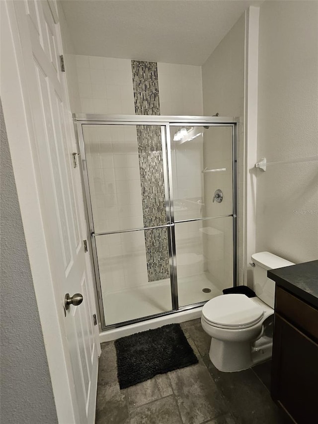 bathroom featuring vanity, toilet, and a shower with shower door