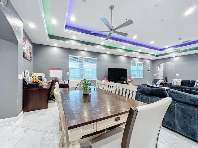 dining room with ceiling fan and a raised ceiling