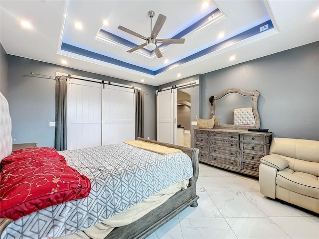 bedroom featuring ceiling fan, a barn door, and a tray ceiling