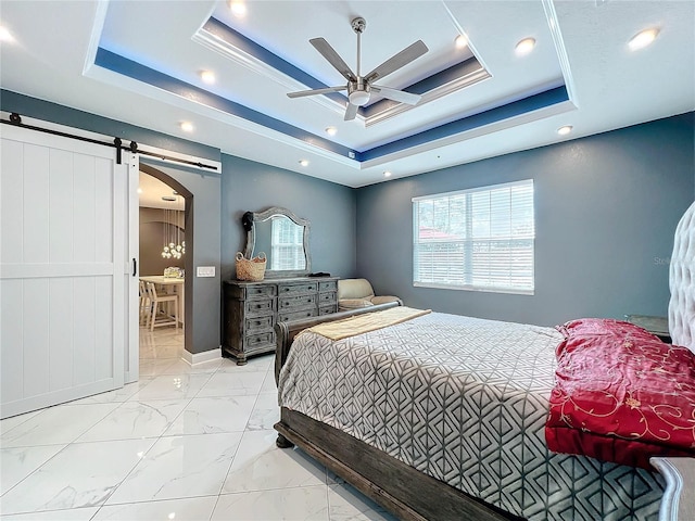 bedroom featuring a tray ceiling, a barn door, and ceiling fan