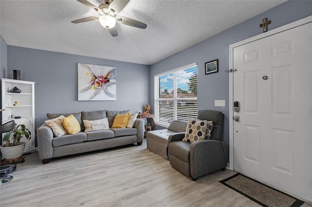 living room featuring ceiling fan, light hardwood / wood-style floors, and a textured ceiling