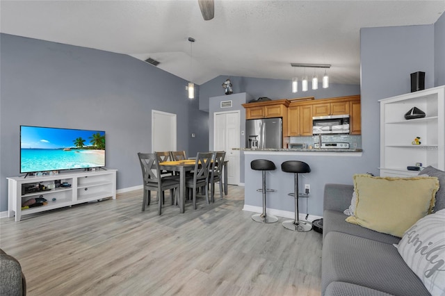 living room with vaulted ceiling, light hardwood / wood-style flooring, and ceiling fan