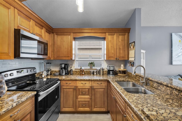 kitchen with light stone countertops, a textured ceiling, stainless steel appliances, and sink