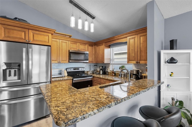 kitchen featuring sink, stainless steel appliances, dark stone counters, vaulted ceiling, and a breakfast bar