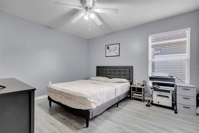 bedroom with ceiling fan, light hardwood / wood-style flooring, and a textured ceiling