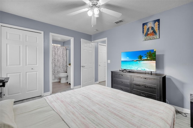 bedroom featuring ceiling fan, light hardwood / wood-style flooring, ensuite bathroom, and a textured ceiling