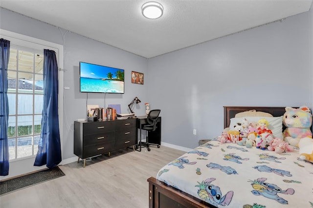 bedroom with light hardwood / wood-style floors and a textured ceiling