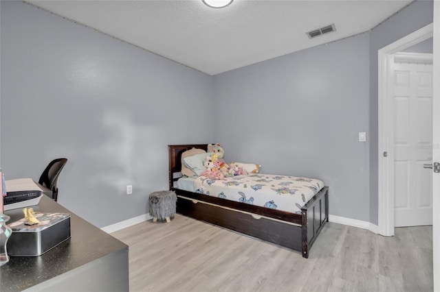 bedroom with light hardwood / wood-style floors and a textured ceiling