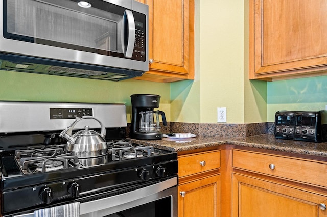 kitchen featuring dark stone counters and stainless steel appliances