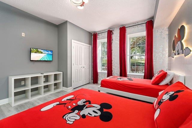 bedroom with a textured ceiling, light hardwood / wood-style floors, and a closet