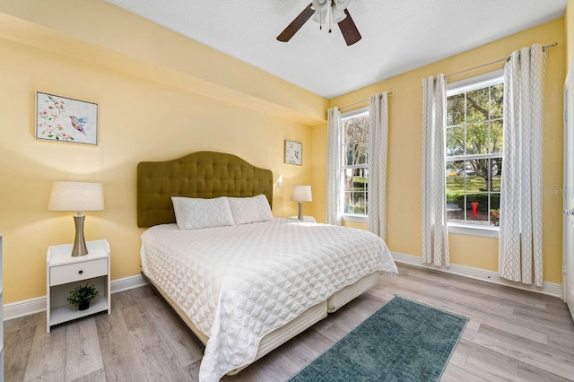 bedroom with a textured ceiling, light wood-type flooring, and ceiling fan