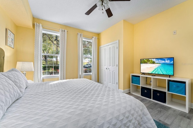 bedroom featuring ceiling fan, wood-type flooring, a textured ceiling, and a closet