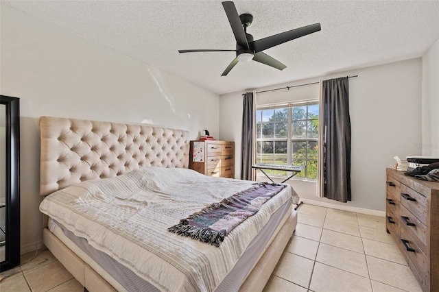 bedroom with ceiling fan, light tile patterned floors, and a textured ceiling