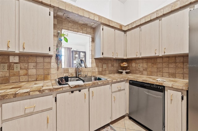 kitchen featuring tasteful backsplash, sink, light tile patterned floors, and stainless steel dishwasher