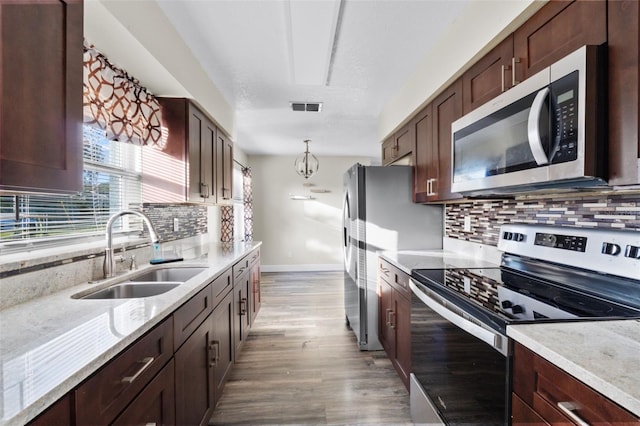 kitchen with decorative backsplash, appliances with stainless steel finishes, hanging light fixtures, and sink