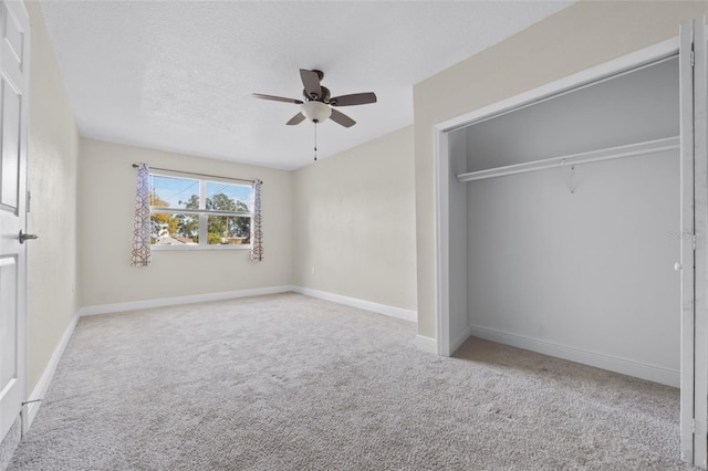 unfurnished bedroom with ceiling fan, a closet, light colored carpet, and a textured ceiling