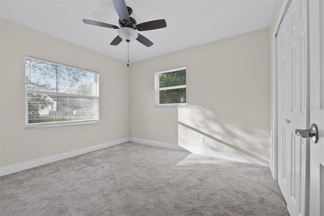 carpeted empty room featuring a wealth of natural light and ceiling fan