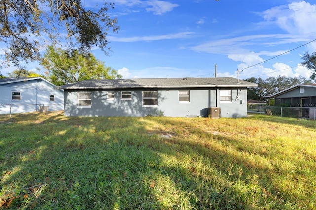 rear view of property with a lawn and central air condition unit