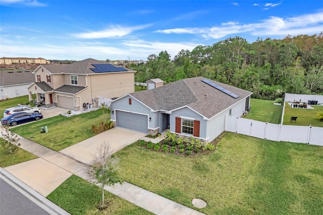 view of front of property featuring a front lawn, a garage, and solar panels