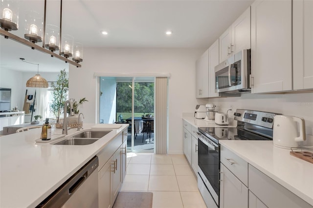 kitchen featuring decorative light fixtures, sink, white cabinetry, and stainless steel appliances