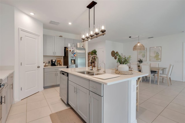 kitchen featuring sink, an island with sink, stainless steel appliances, and decorative light fixtures