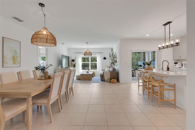 dining area featuring sink, light tile patterned floors, and a notable chandelier