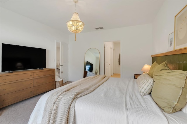 bedroom with carpet flooring, ensuite bathroom, and a notable chandelier