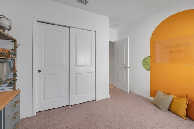 bedroom with light carpet and a closet