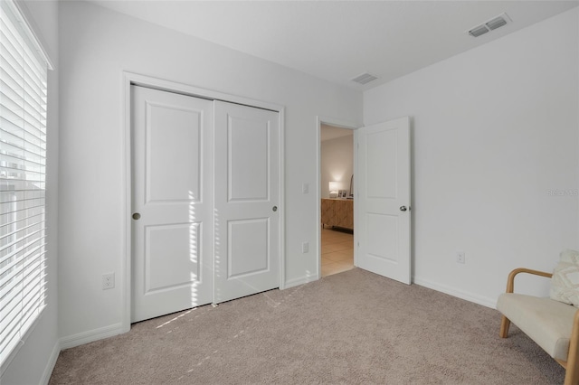 unfurnished bedroom with light carpet and a closet