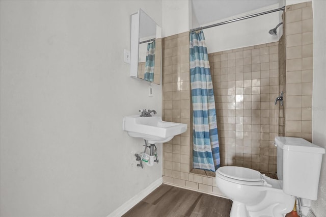 bathroom with hardwood / wood-style floors, toilet, and curtained shower