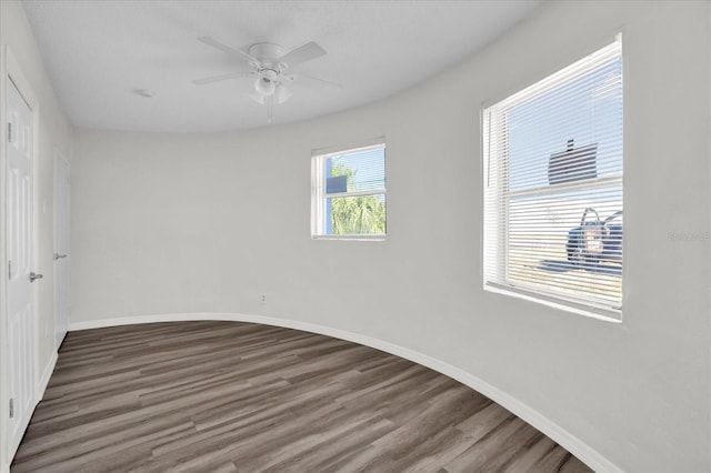 spare room with ceiling fan, plenty of natural light, and dark hardwood / wood-style floors