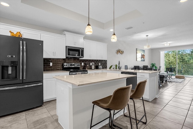 kitchen with white cabinets, a center island, a tray ceiling, and appliances with stainless steel finishes