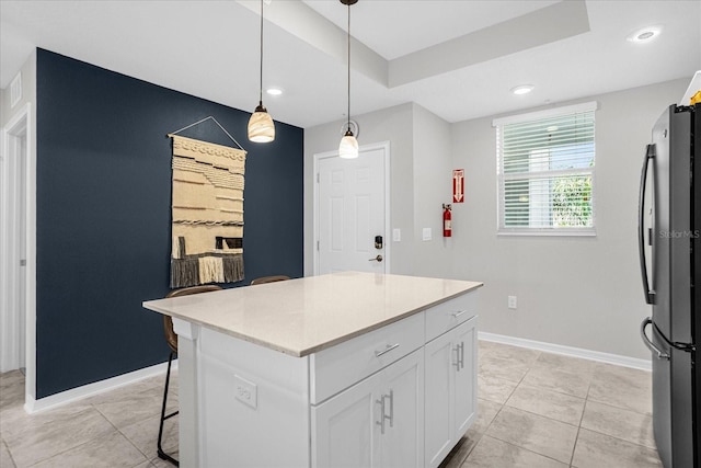 kitchen with a center island, decorative light fixtures, light tile patterned floors, white cabinetry, and stainless steel refrigerator