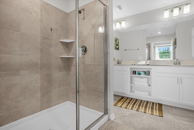 bathroom with a shower with door, tile patterned flooring, and vanity