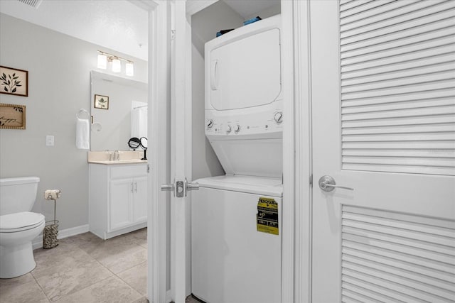 washroom with sink, light tile patterned floors, and stacked washer and dryer