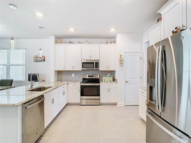 kitchen with white cabinets, sink, appliances with stainless steel finishes, decorative light fixtures, and kitchen peninsula