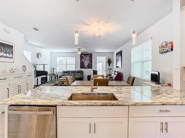 kitchen featuring white cabinets, pendant lighting, stainless steel dishwasher, and sink