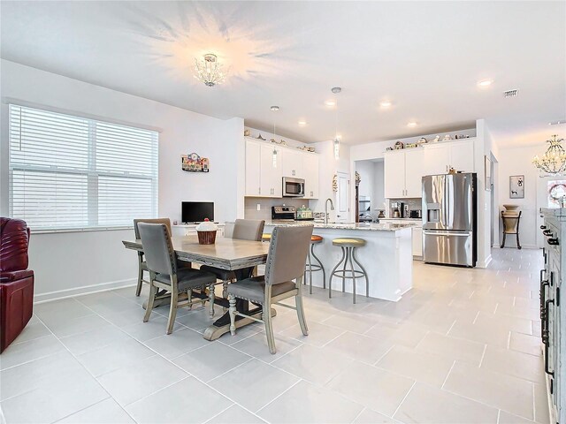 dining area with light tile patterned floors, sink, and an inviting chandelier