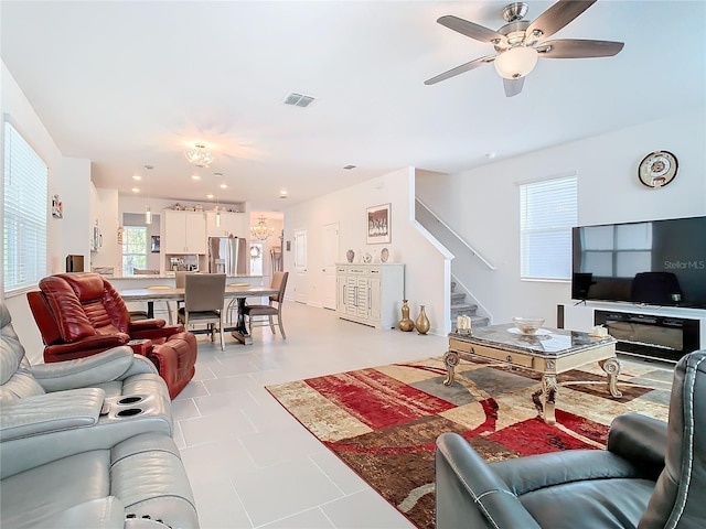 living area featuring visible vents, a ceiling fan, and stairs