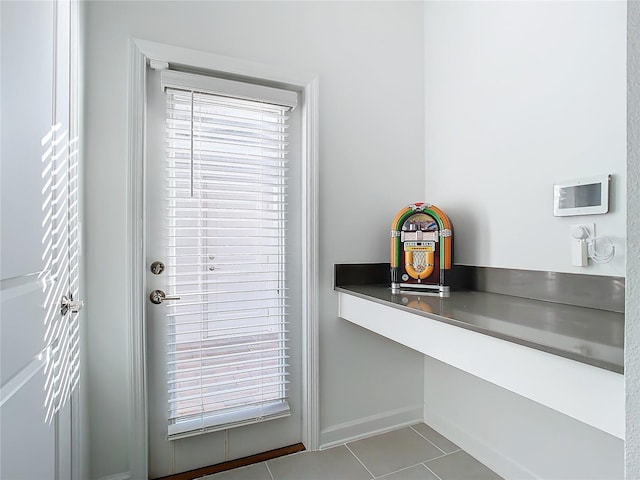doorway with tile patterned floors and baseboards