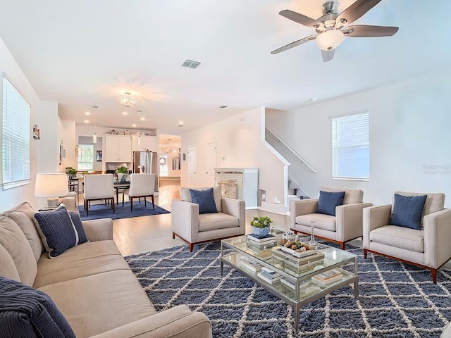living area featuring wood finished floors, visible vents, stairs, and ceiling fan