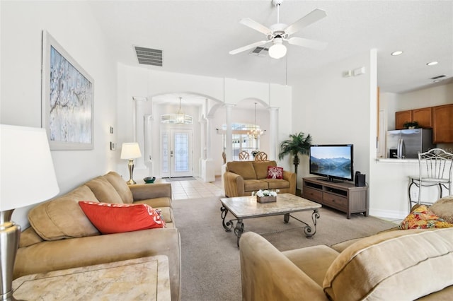 carpeted living room featuring ceiling fan with notable chandelier, french doors, and decorative columns