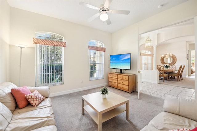 living room featuring light carpet and ceiling fan with notable chandelier