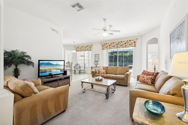 carpeted living room featuring ceiling fan and a textured ceiling