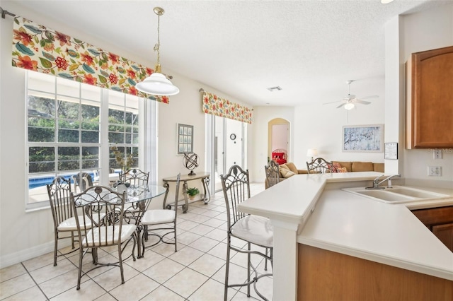 kitchen with light tile patterned floors, decorative light fixtures, ceiling fan, and sink