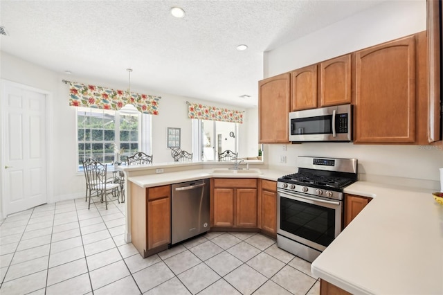 kitchen featuring sink, hanging light fixtures, kitchen peninsula, a textured ceiling, and appliances with stainless steel finishes