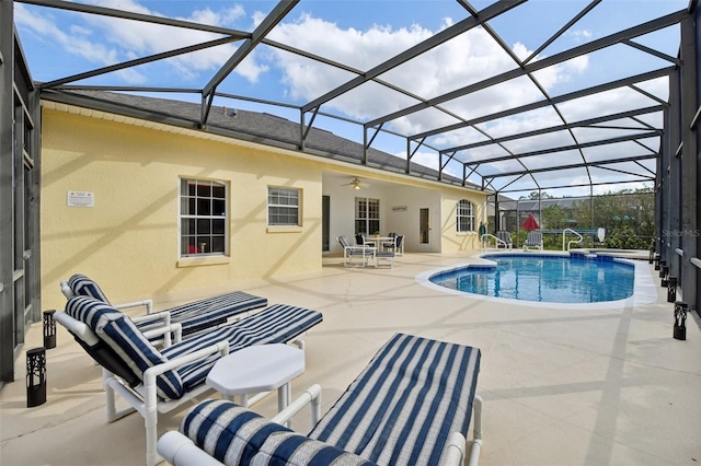 view of swimming pool with glass enclosure, ceiling fan, and a patio area