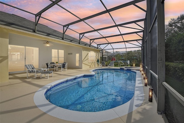 pool at dusk featuring glass enclosure and a patio